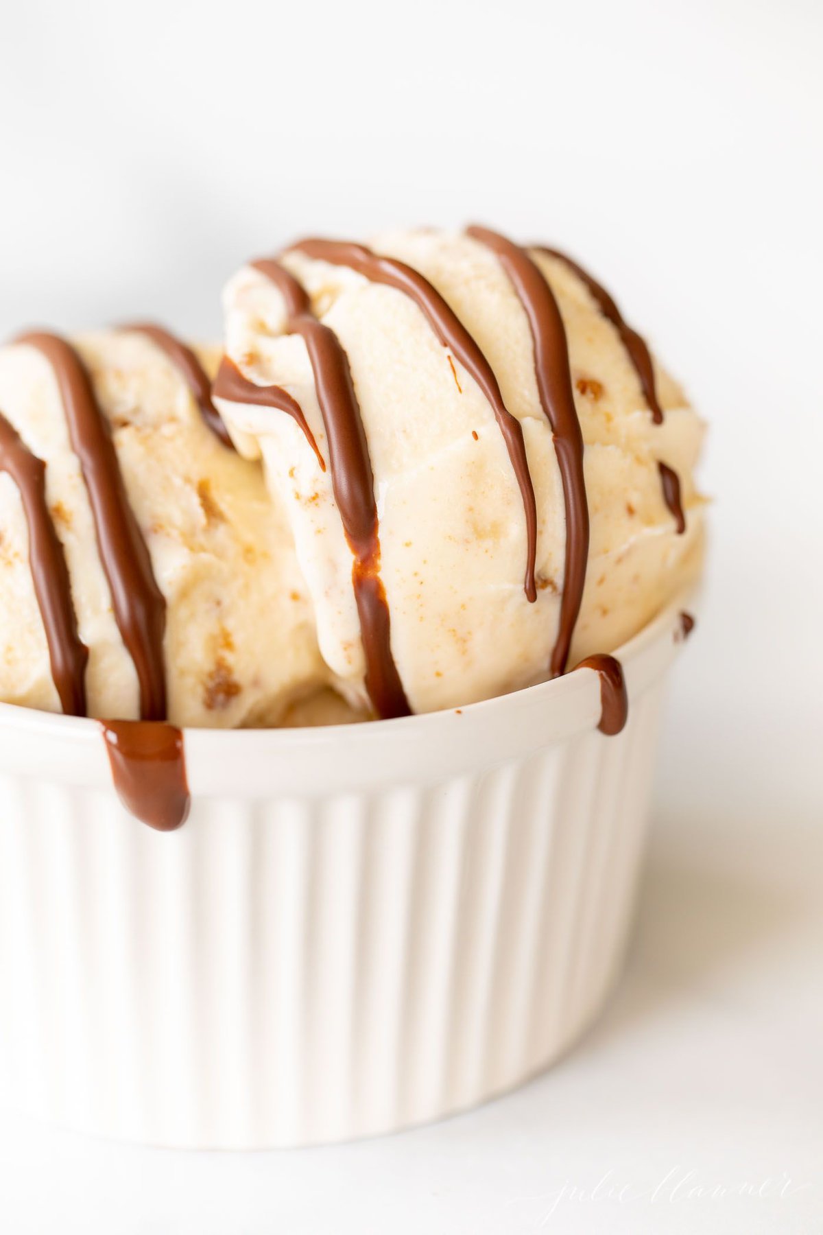 A white bowl of ice cream topped with chocolate magic shell.