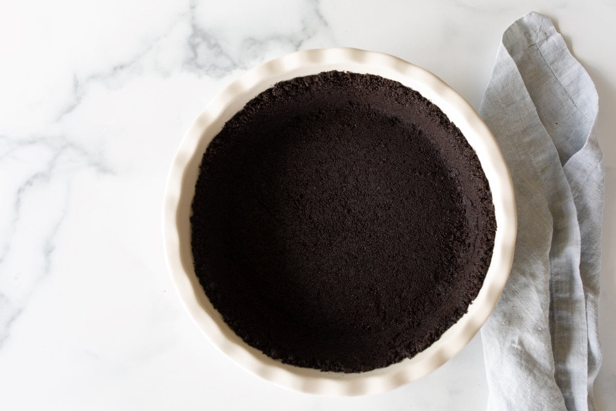 A white ceramic pie dish with an oreo crust recipe inside.