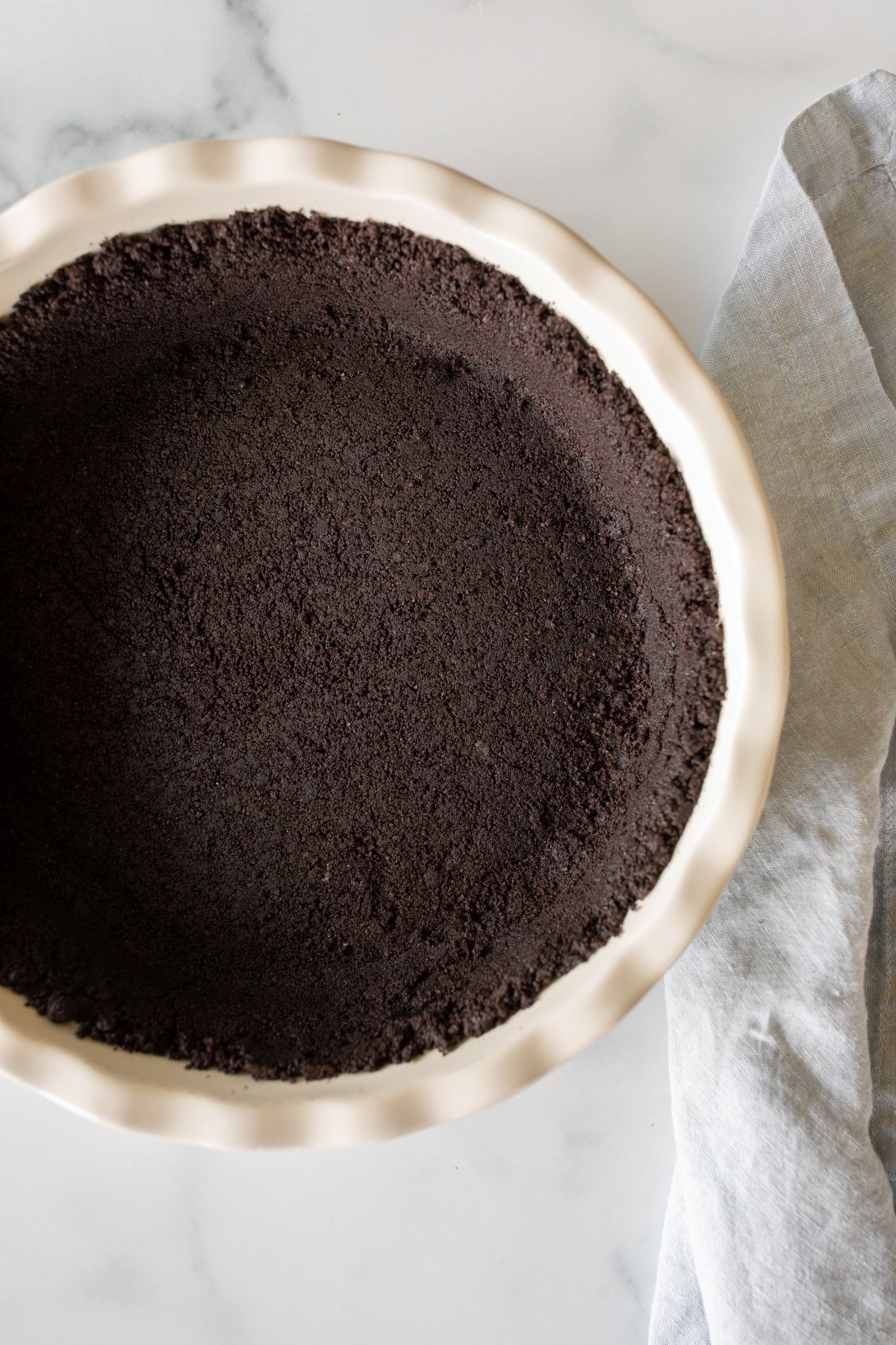 An oreo cookie crust inside a white pie pan.