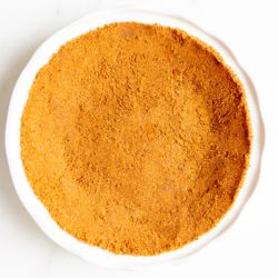 A white pie pan full of speculoos cookie crust for a pie.