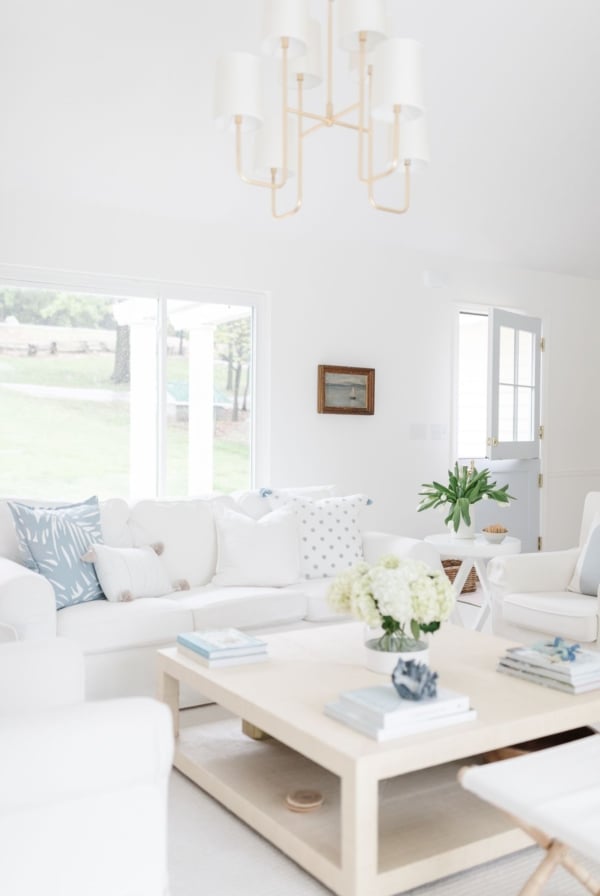 A white living room with white furniture and a raffia coffee table