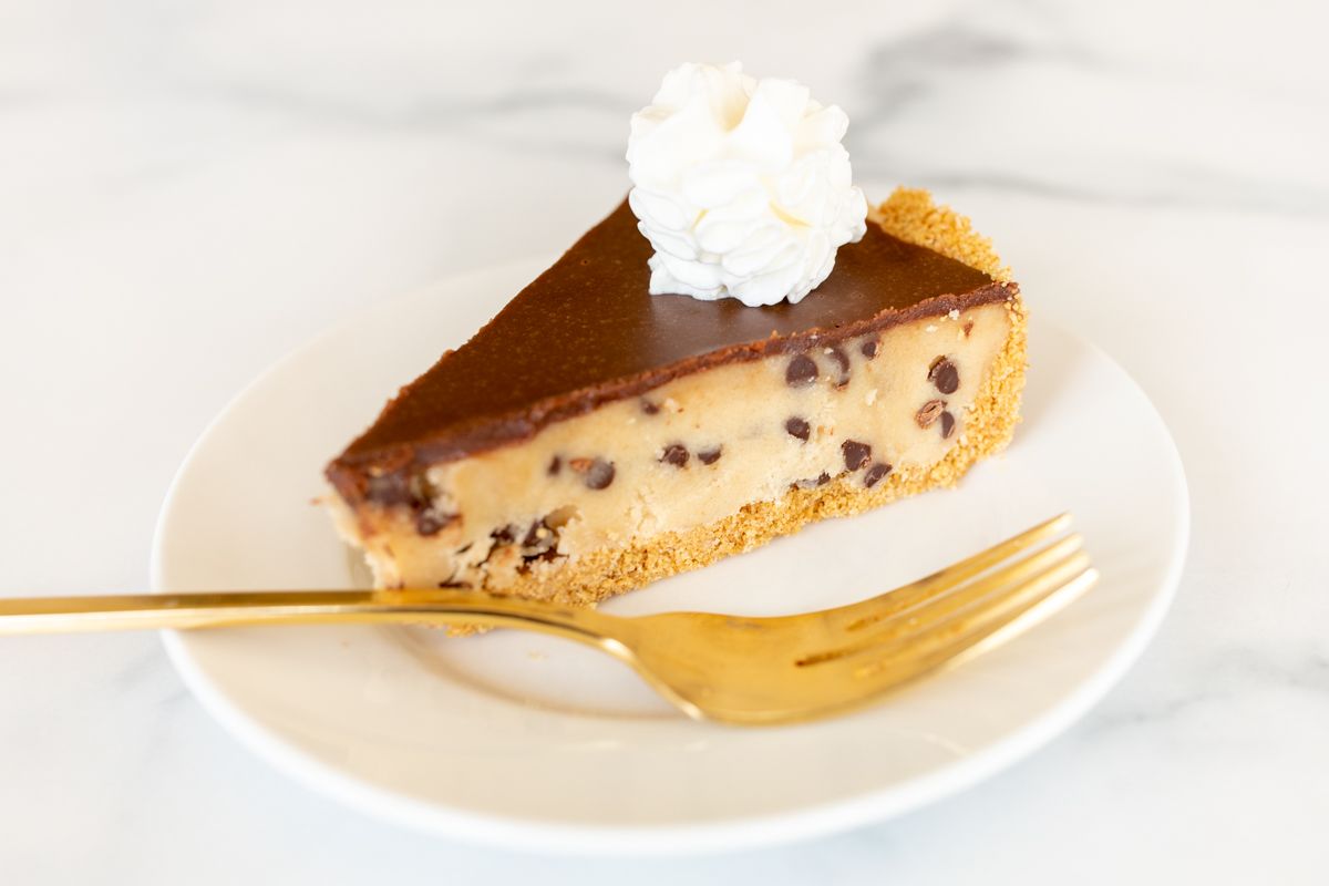 A white plate with a slice of cookie dough pie and a gold fork.