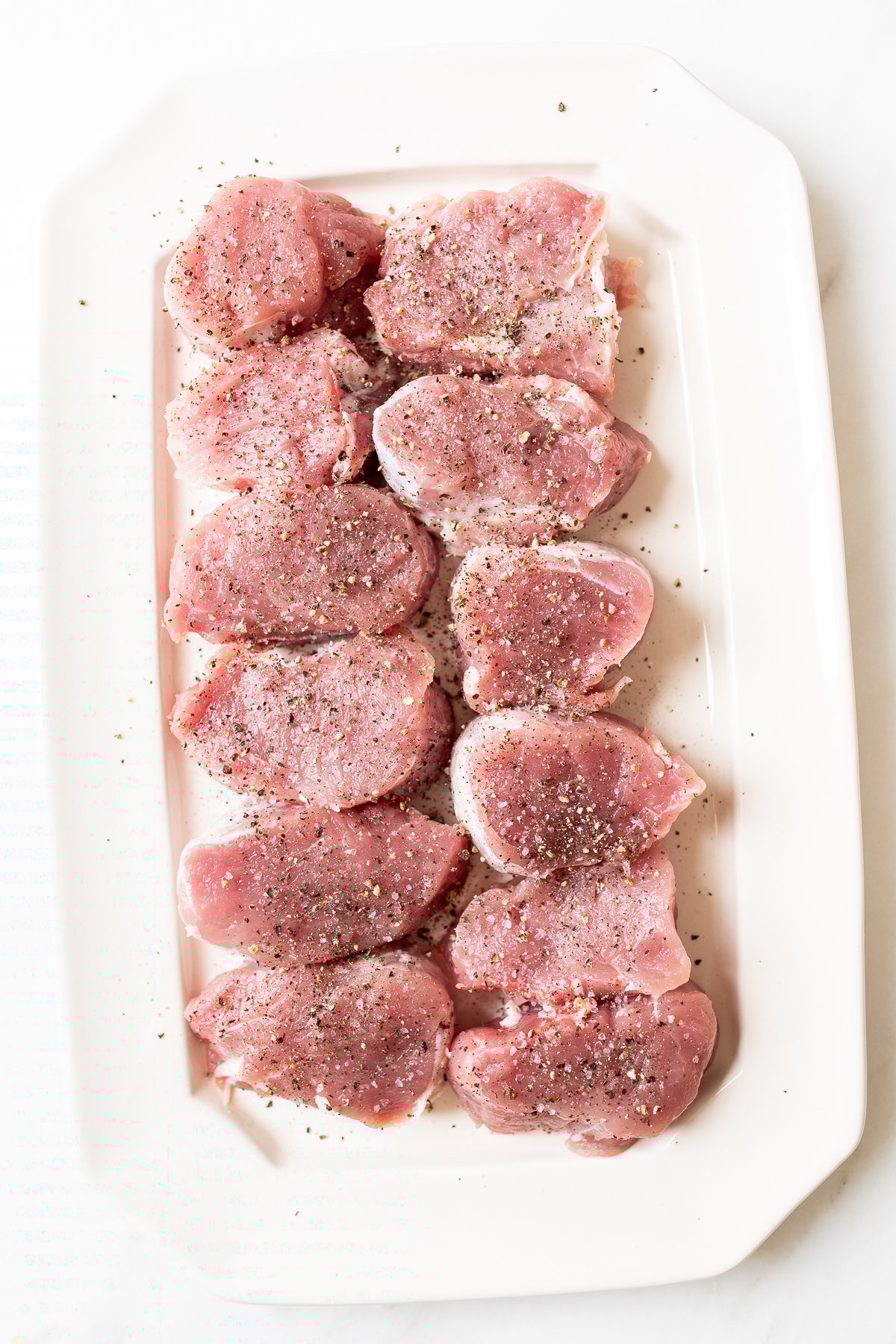 Pork tenderloin medallions on a white tray.
