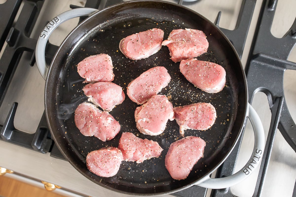 Pork tenderloin medallions in a cast iron skillet.