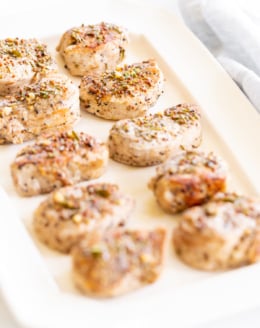 Apple cider pork tenderloin medallions on a white platter.