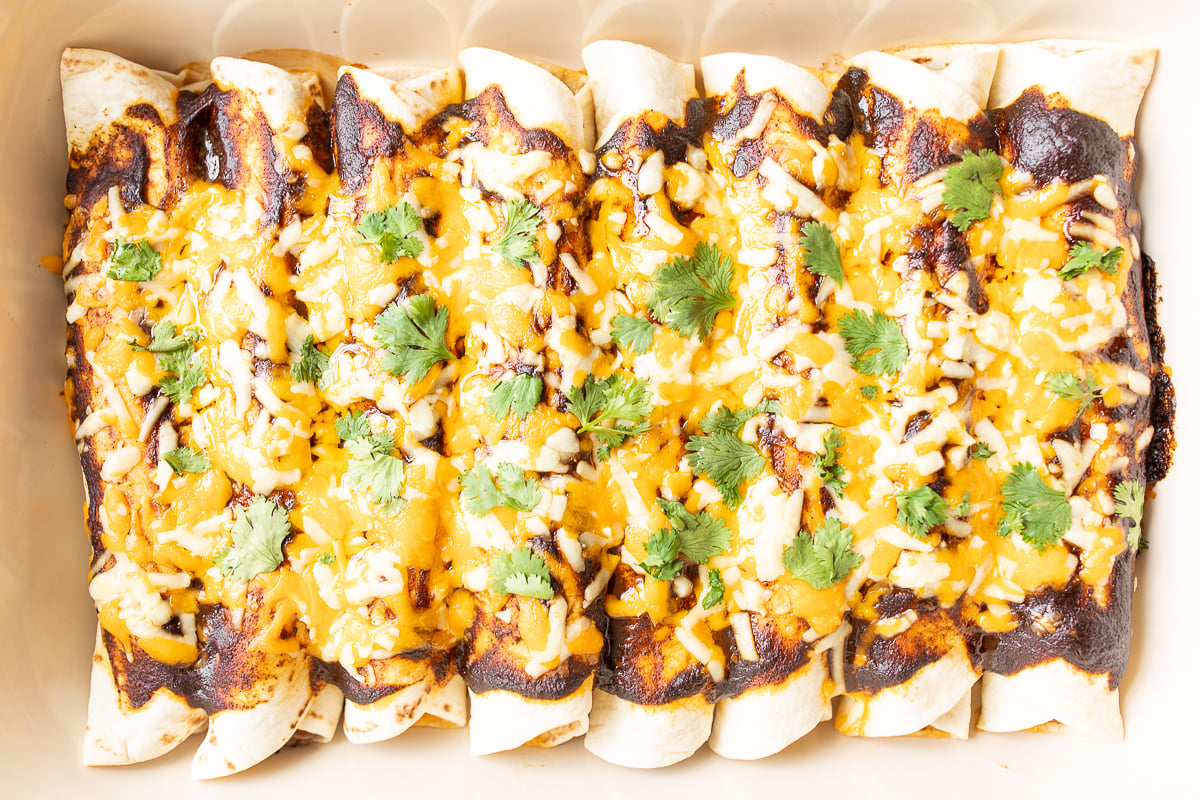 A white pan full of beef enchiladas.