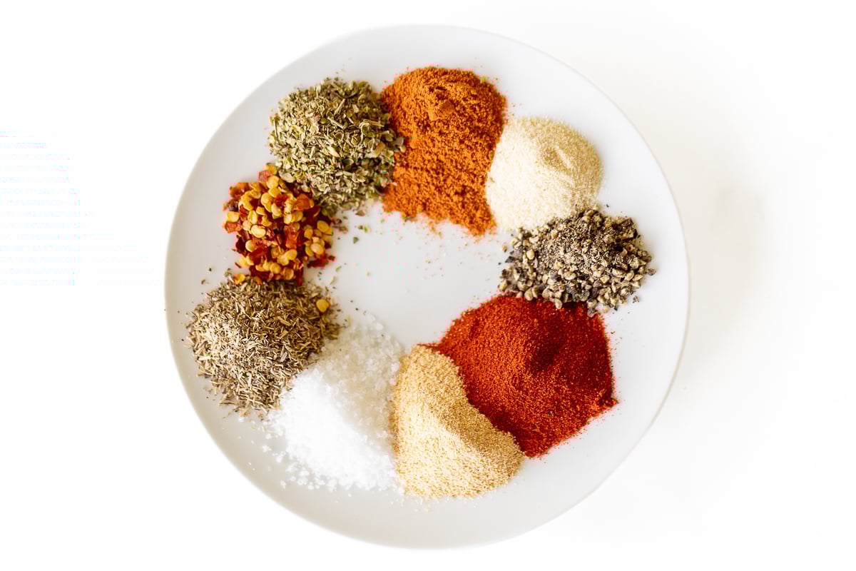 Various spices on a white plate for a homemade cajun seasoning recipe.