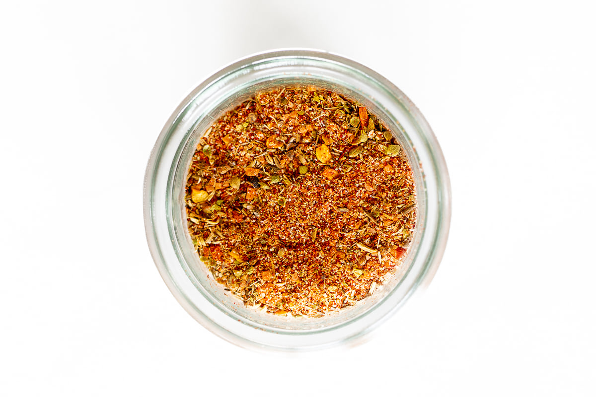 A small glass jar full of cajun seasoning.
