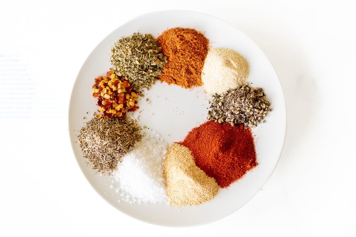 Various spices on a white plate for a homemade cajun seasoning recipe.