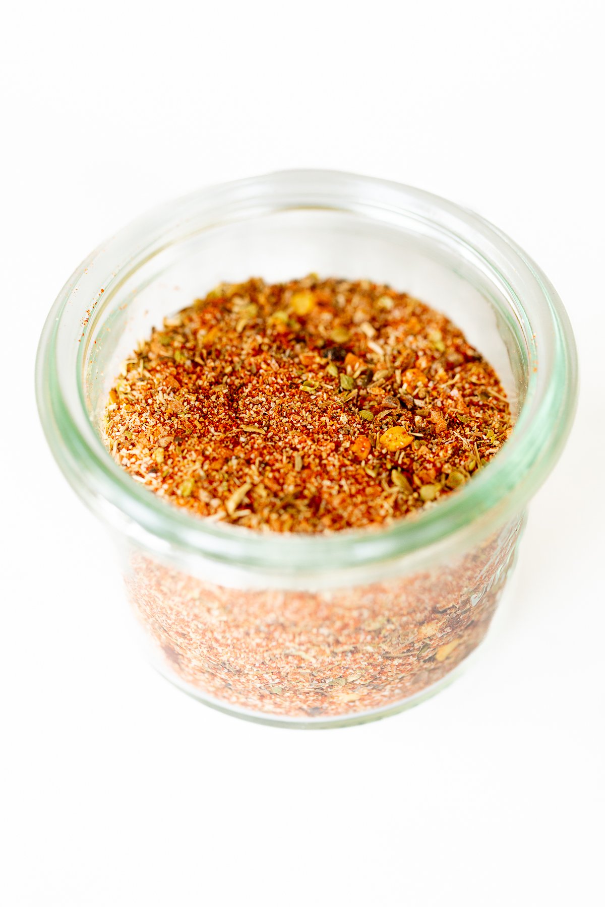 A small glass jar full of cajun seasoning.