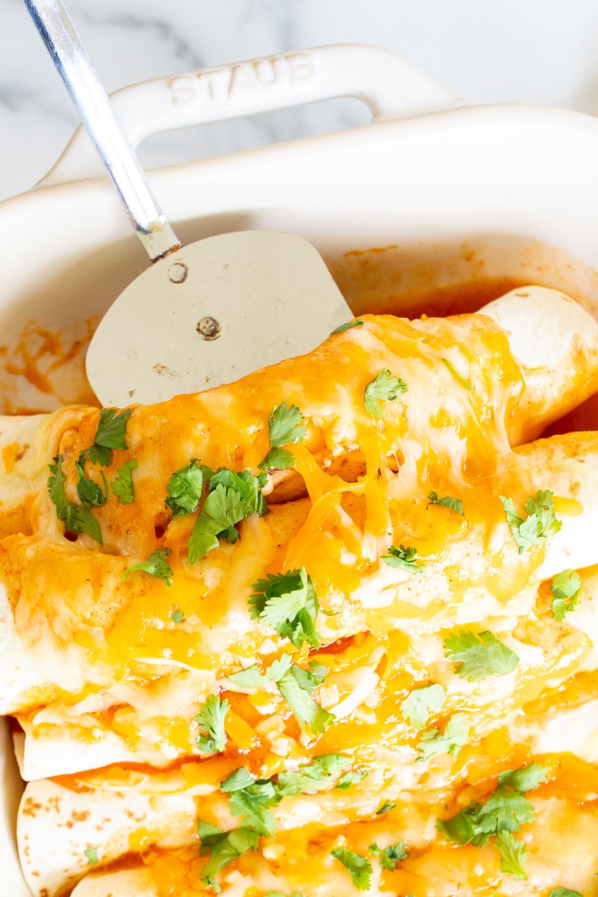 A white baking dish full of chicken enchiladas.