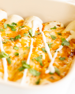 A white baking dish full of chicken enchiladas.