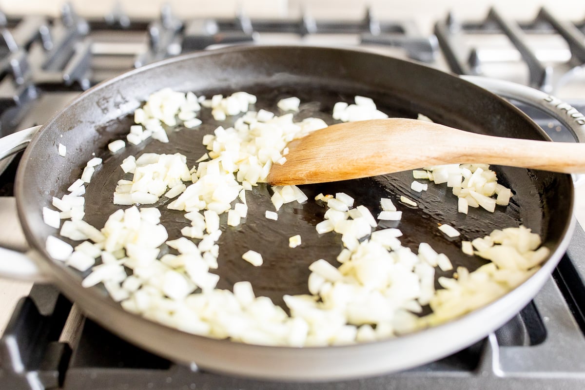 Small pieces of onion cooking in a cast iron skillet