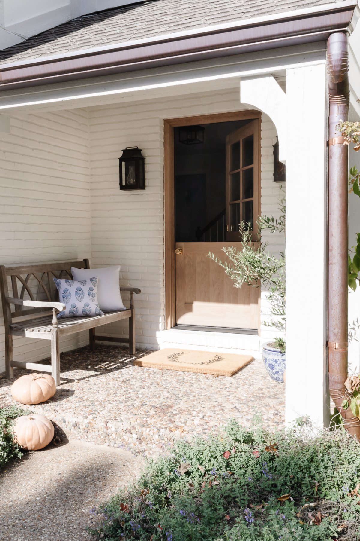 A fall front porch with blue and white accents and peach heirloom pumpkins.