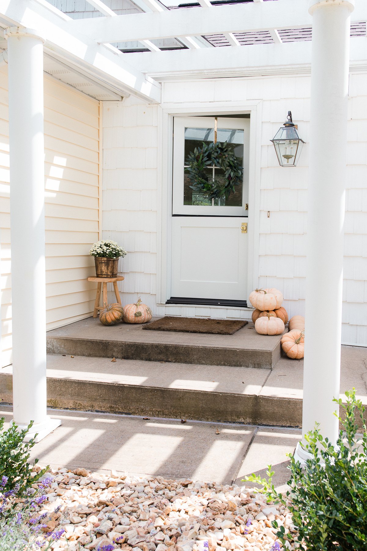 Fall porch decor with peach heirloom pumpkins, and a fall wreath on a Dutch door.