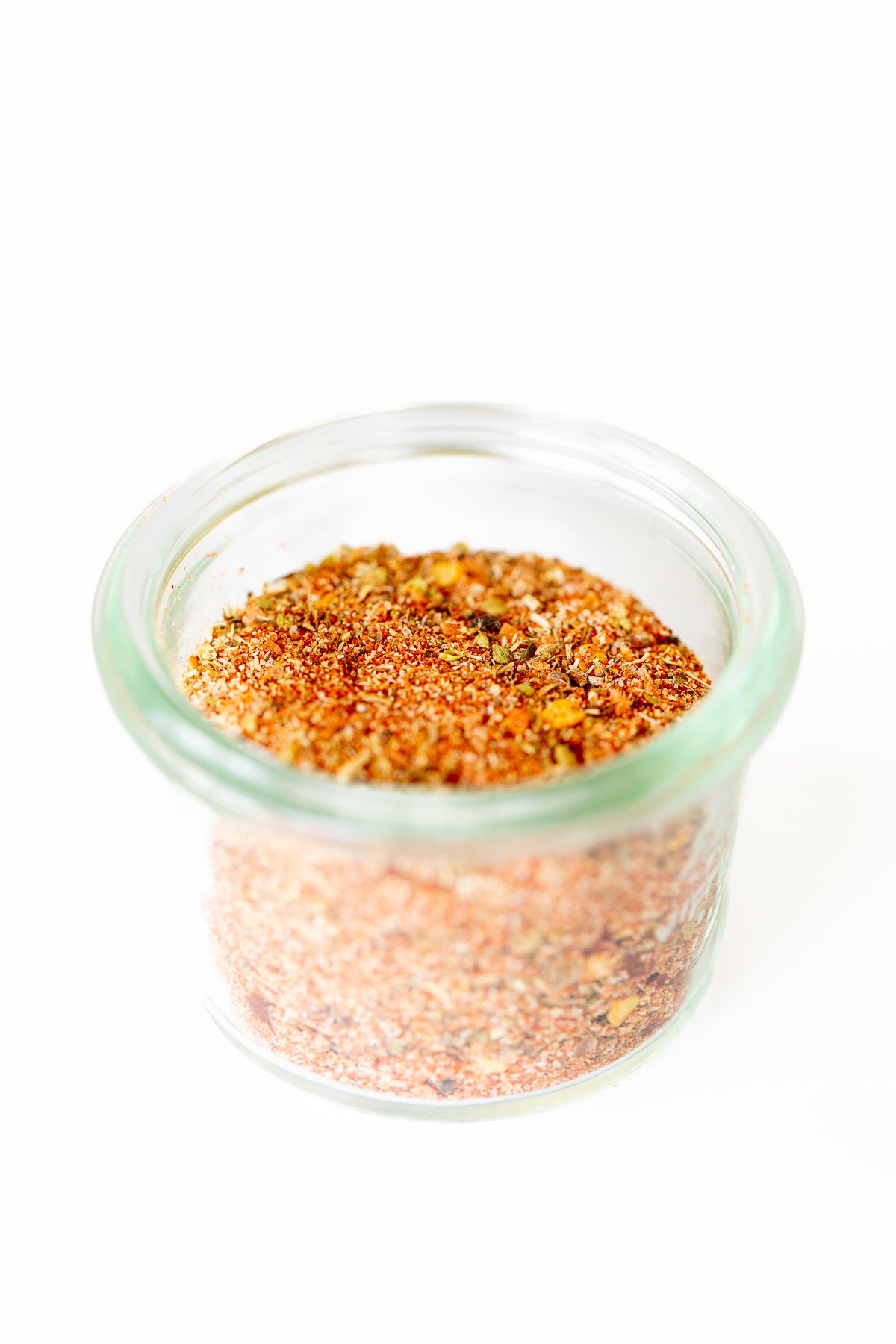 A small glass jar full of cajun seasoning.