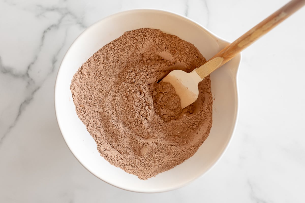 Homemade hot chocolate in a white bowl with a wooden spoon.