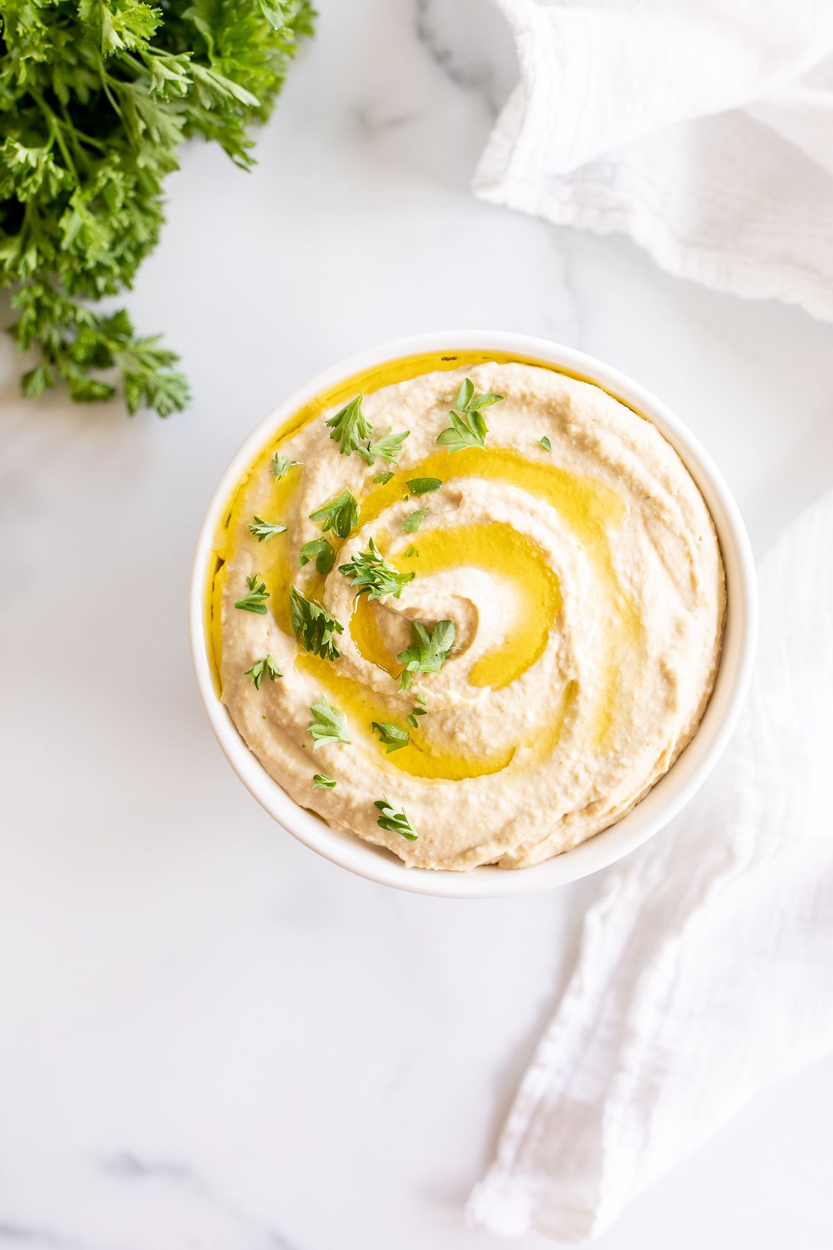 A small bowl of an easy hummus recipe on a white countertop.