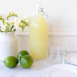 margarita mix next to limes and rimmed glass