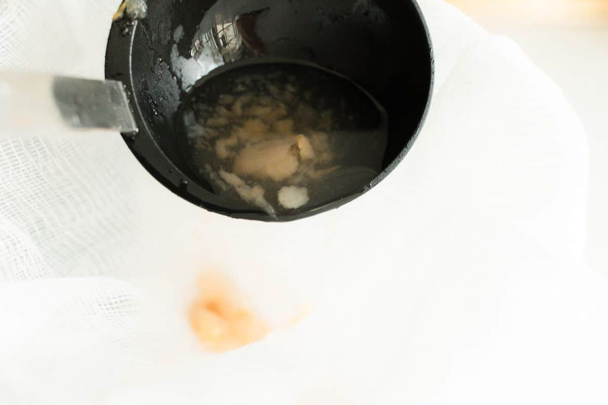 Learning how to make pear cider by straining the cider through a sieve.