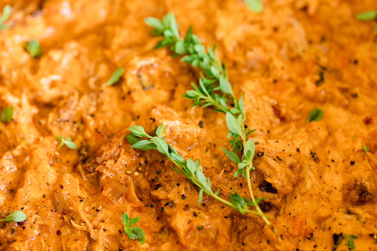 close up of pork ragu, garnished with stems of fresh thyme