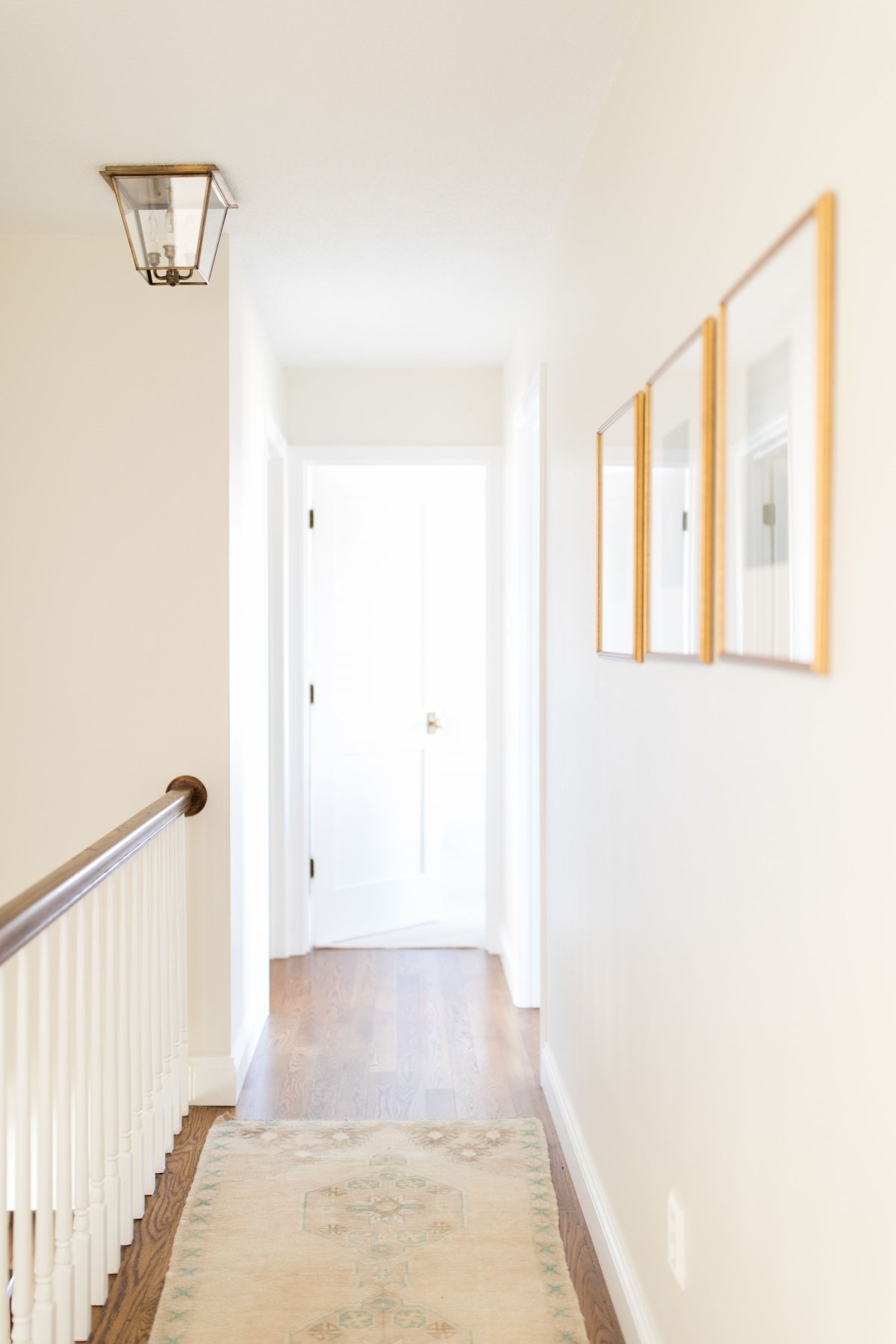 A white hallway in the upstairs of a home, with a vintage Turkish rug on the floor.