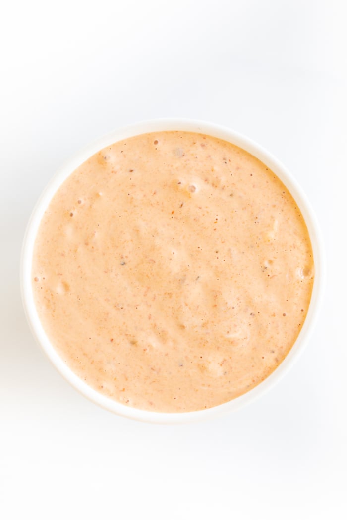 A white bowl of chipotle aioli on a white marble countertop.