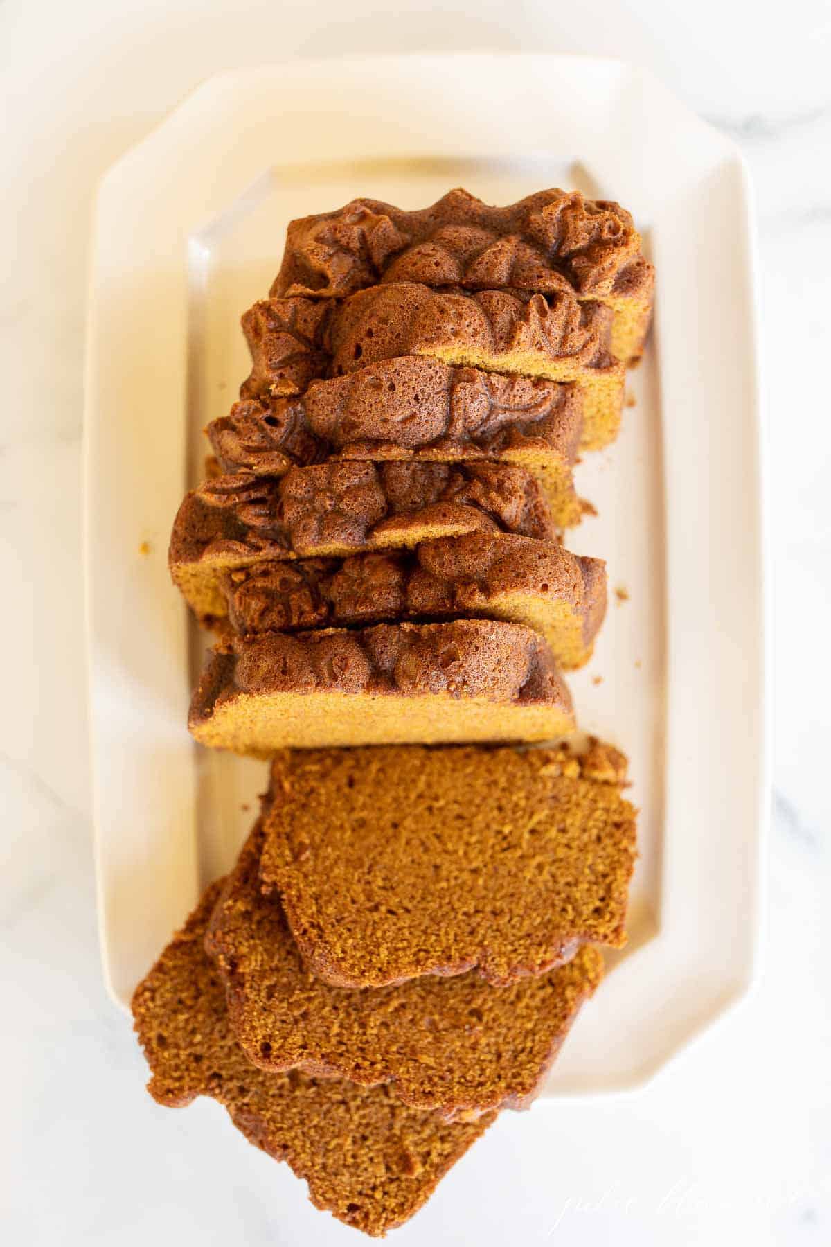 A white platter with a pumpkin bread recipe cut into slices