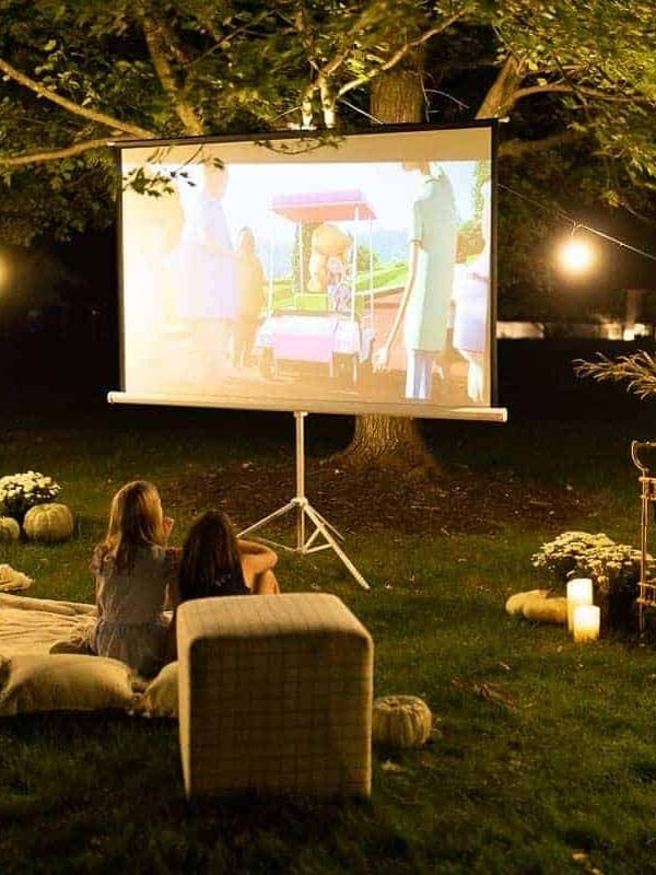 An outdoor movie set up in a yard for halloween, with a skeleton, candles and decorations.