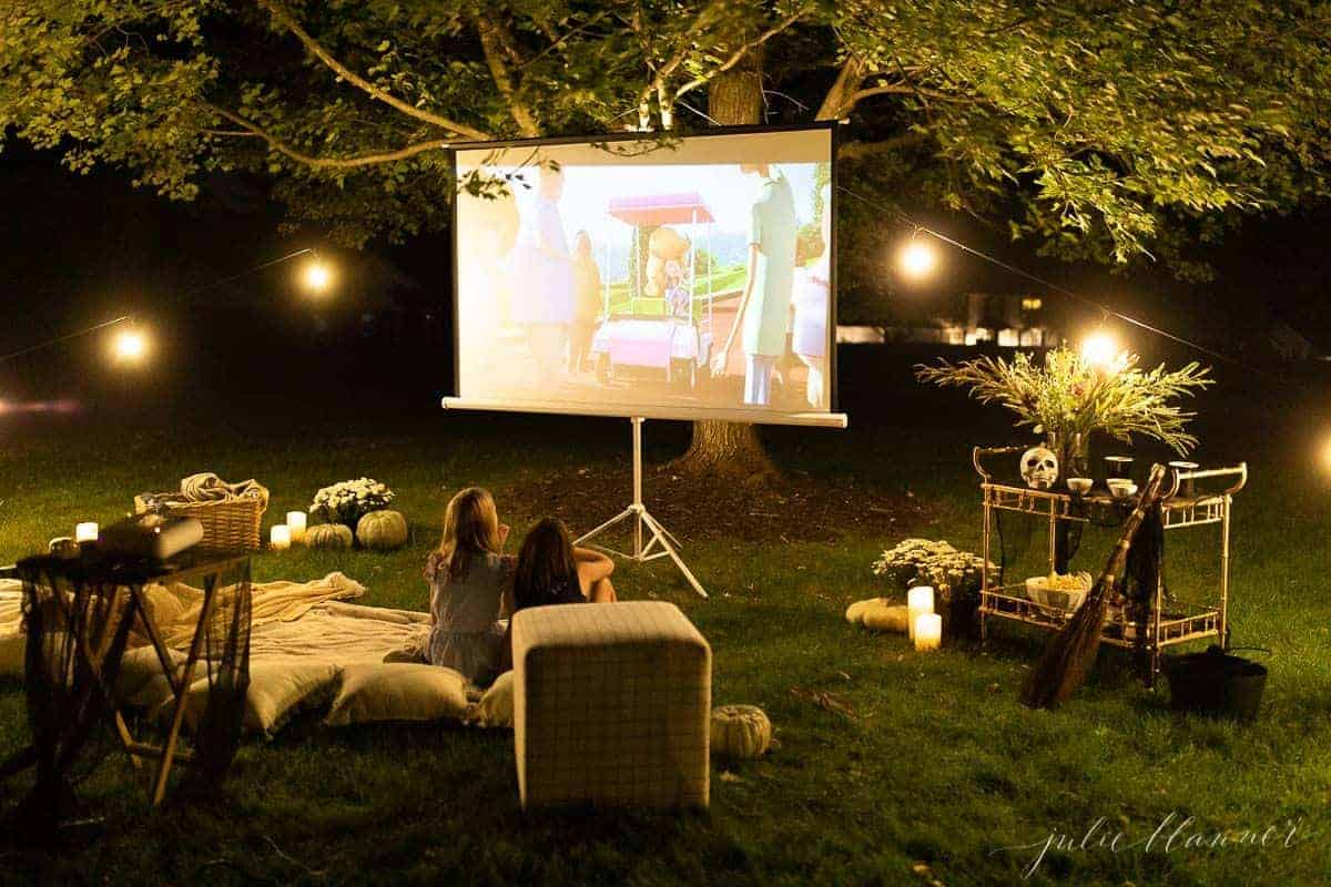 An outdoor movie set up in a yard for halloween, with a skeleton, candles and decorations.