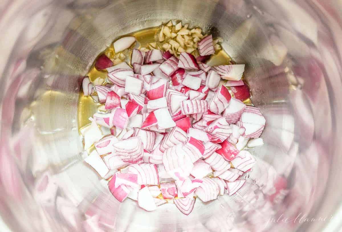 A pot full of sliced onions, garlic and olive oil for an instant pot minestrone soup recipe.