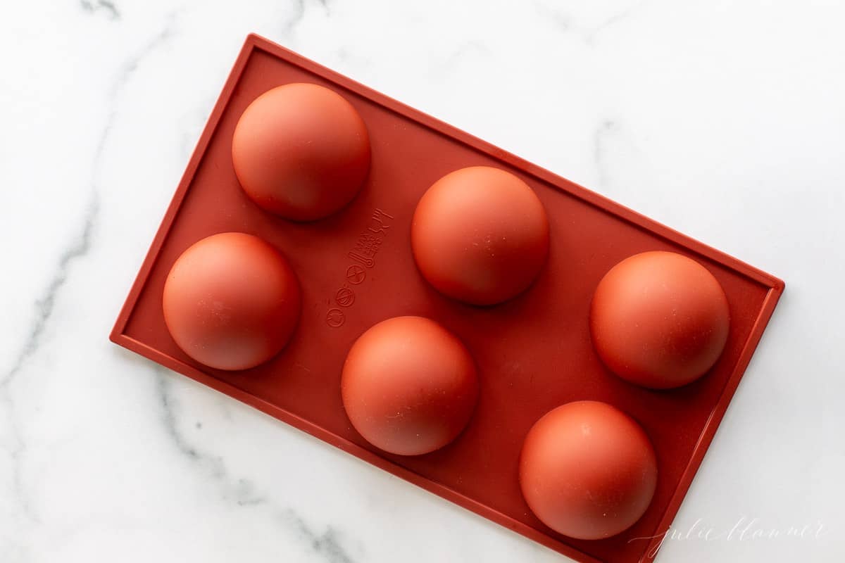 A marble surface with a red silicone sphere mold.