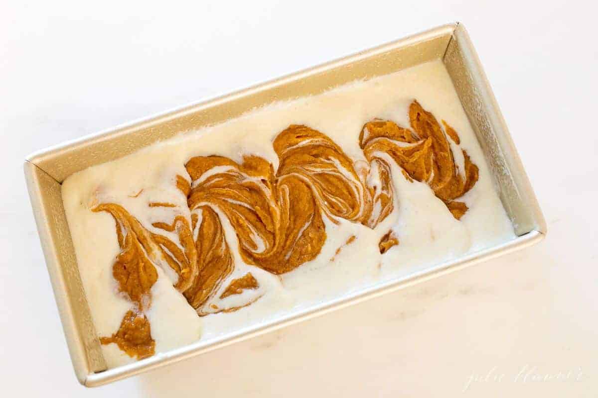 A gold loaf pan filled with pumpkin cheesecake bread.