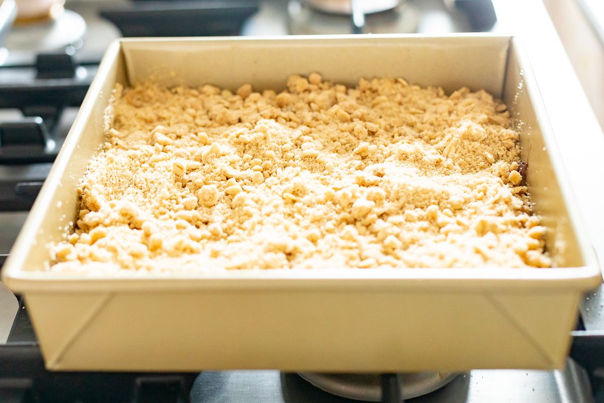 Caramel oatmeal chocolate chip bars in a gold baking pan on a stovetop.