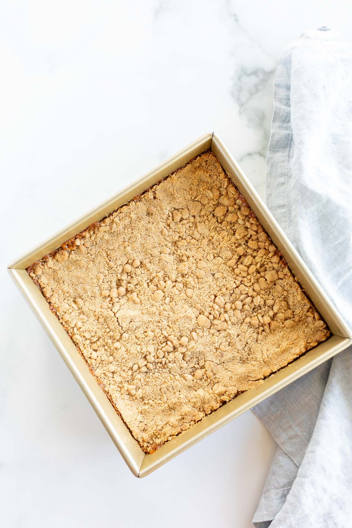 Caramel oatmeal chocolate chip bars baked in a gold baking pan.