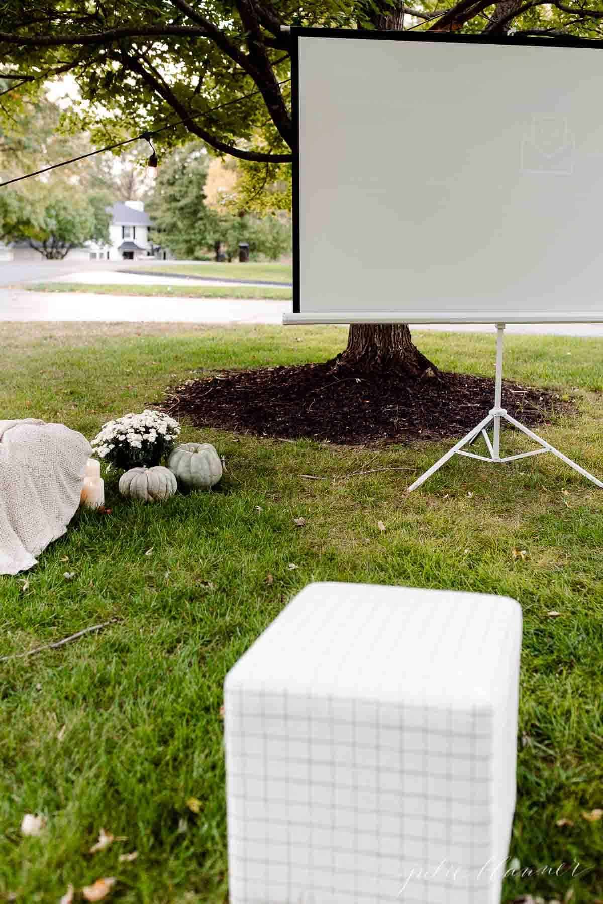 A yard set up with an outdoor movie projector screen in the fall.