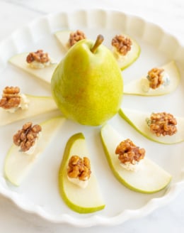 Walnut, blue cheese and sliced pear appetizers on a white platter.