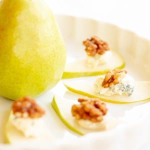 Walnut, blue cheese and sliced pear appetizers on a white platter.