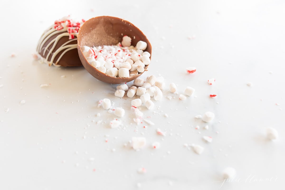 A peppermint hot chocolate bomb, resembling a chocolate egg, filled with peppermint marshmallows and sprinkles.