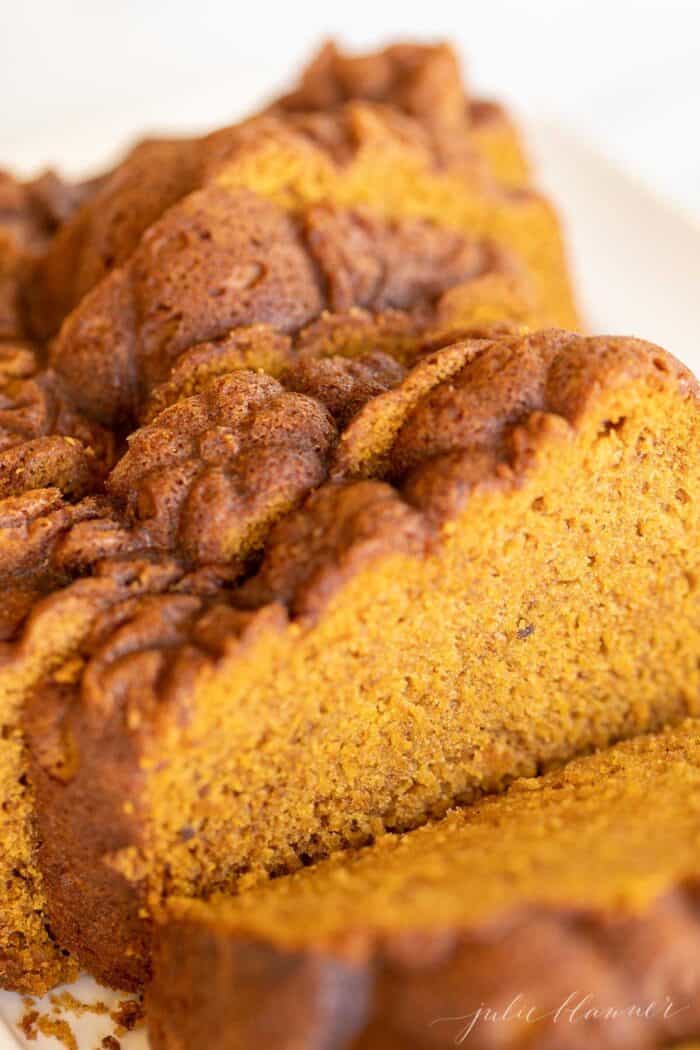 A white platter with a pumpkin bread recipe cut into slices