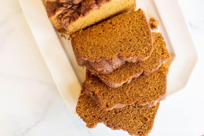 A white platter with a pumpkin bread recipe cut into slices