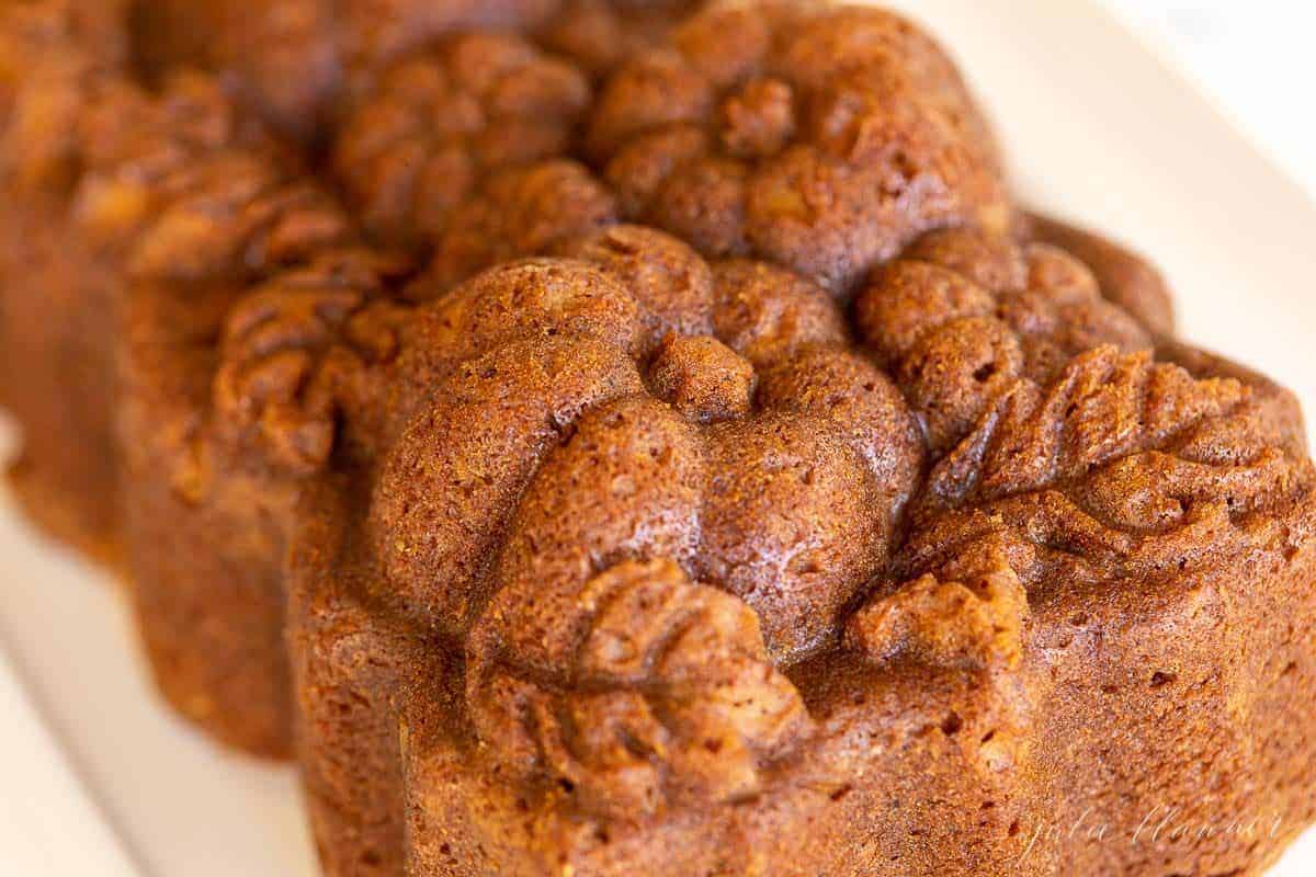 A white platter with a loaf of pumpkin bread shaped into a pumpkin loaf pan.