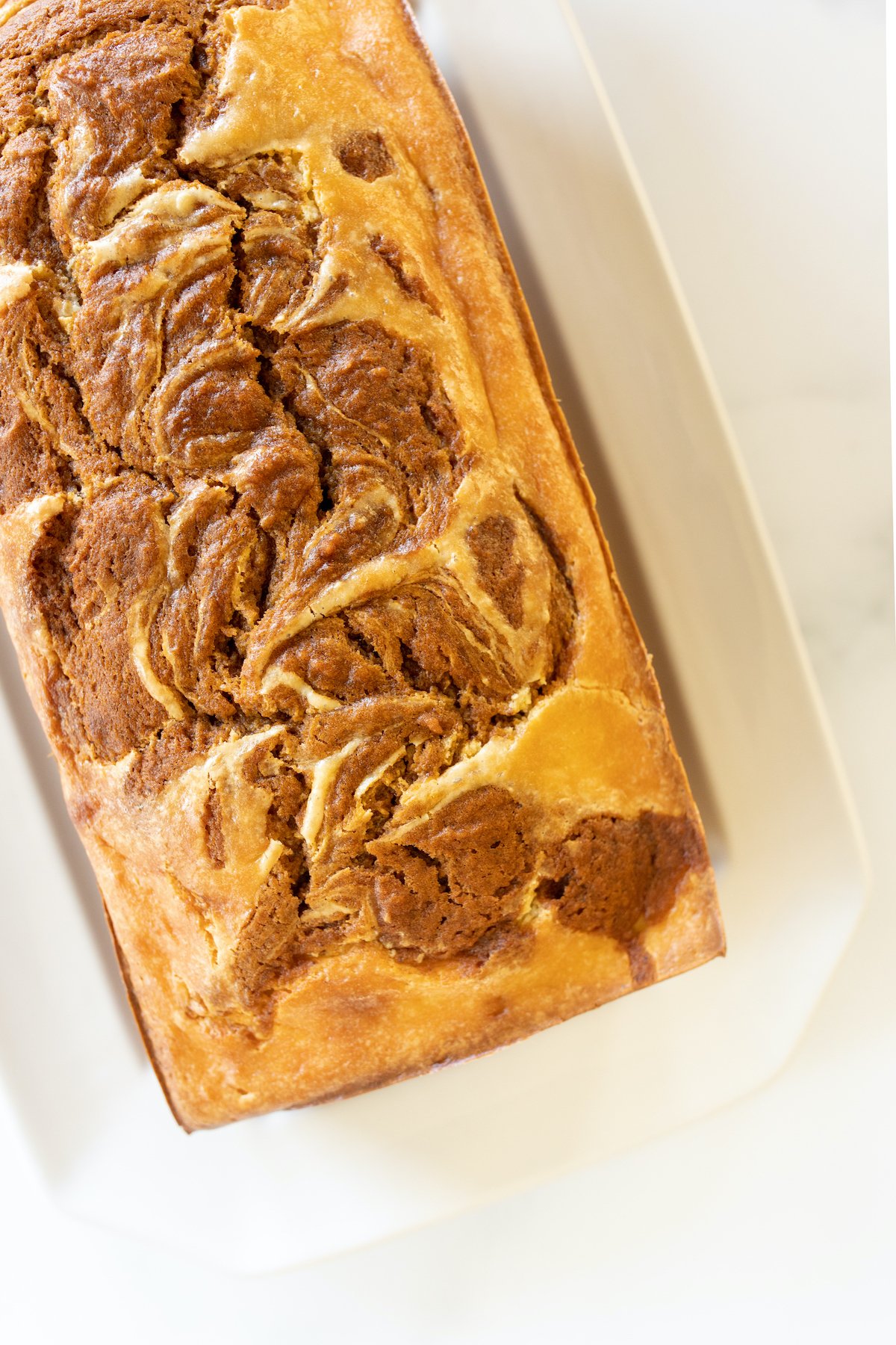 A loaf of pumpkin cheesecake bread on a white platter.