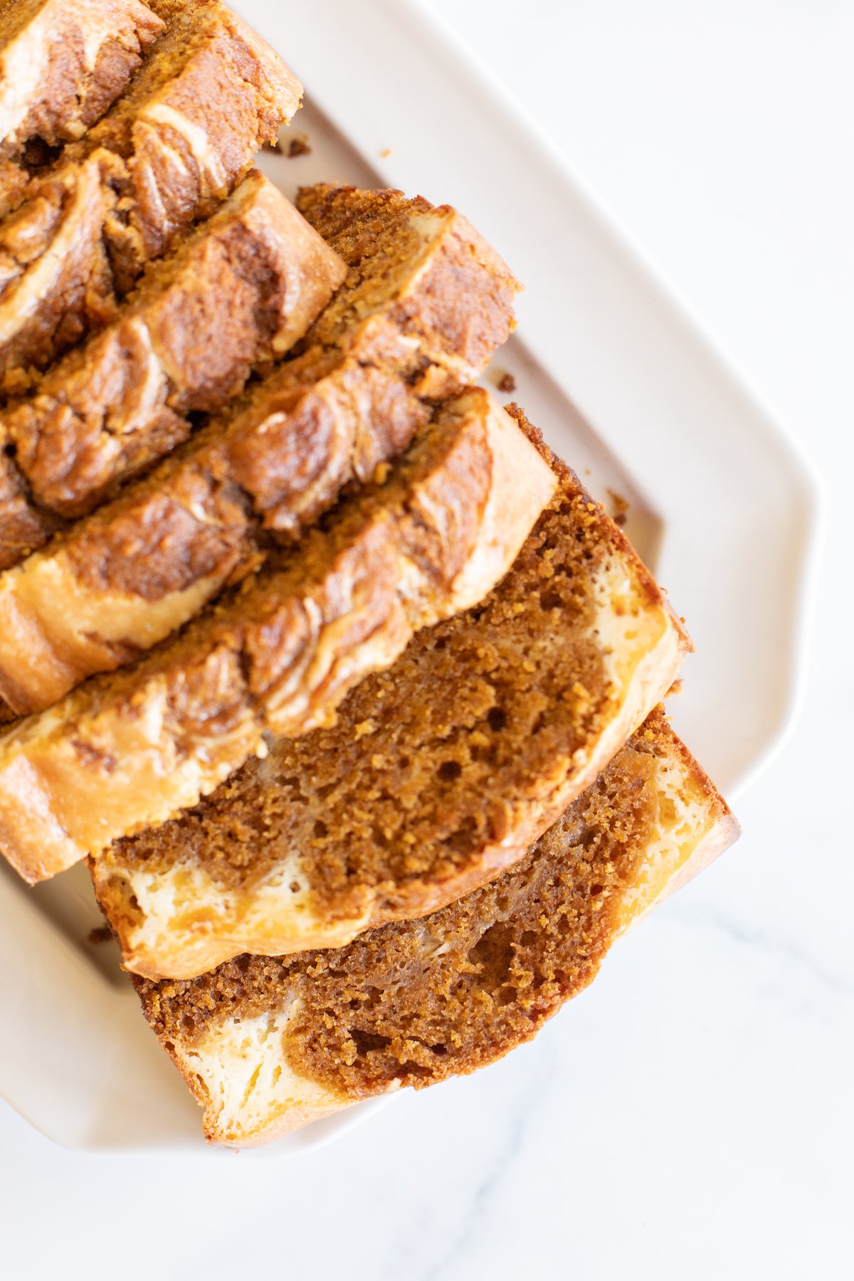 A loaf of pumpkin cheesecake bread on a white platter.