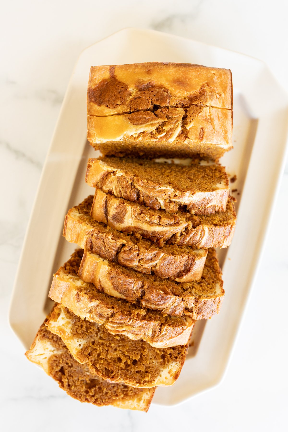 A loaf of pumpkin cheesecake bread on a white platter.