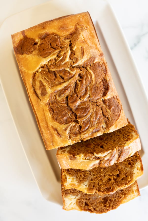 A loaf of pumpkin cheesecake bread on a white platter.