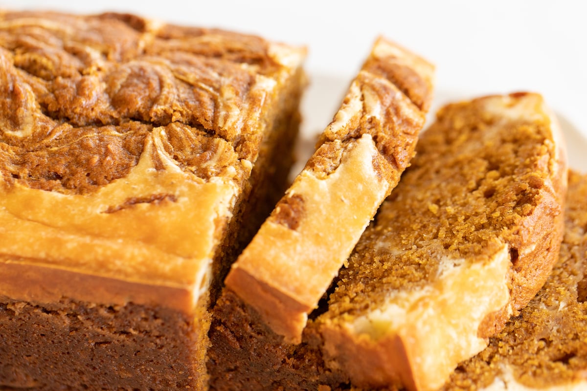 A loaf of pumpkin cheesecake bread on a white platter.