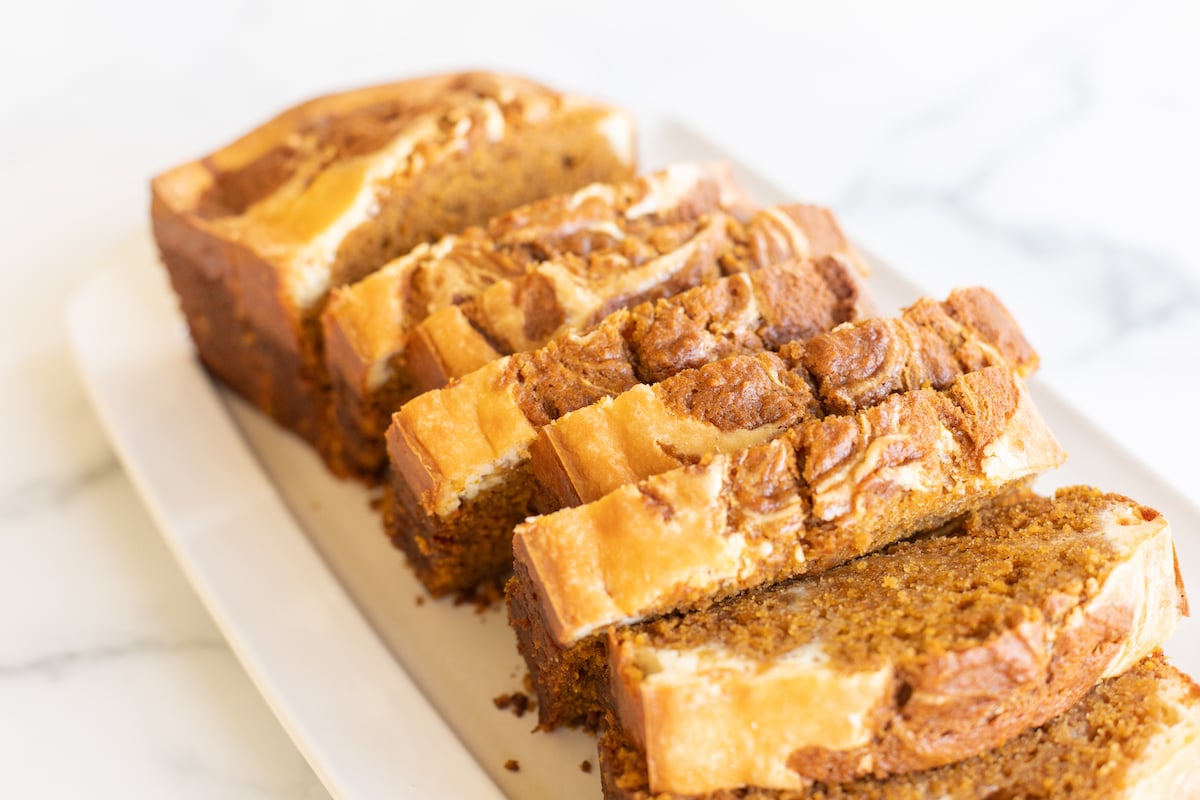 A loaf of pumpkin cheesecake bread on a white platter.