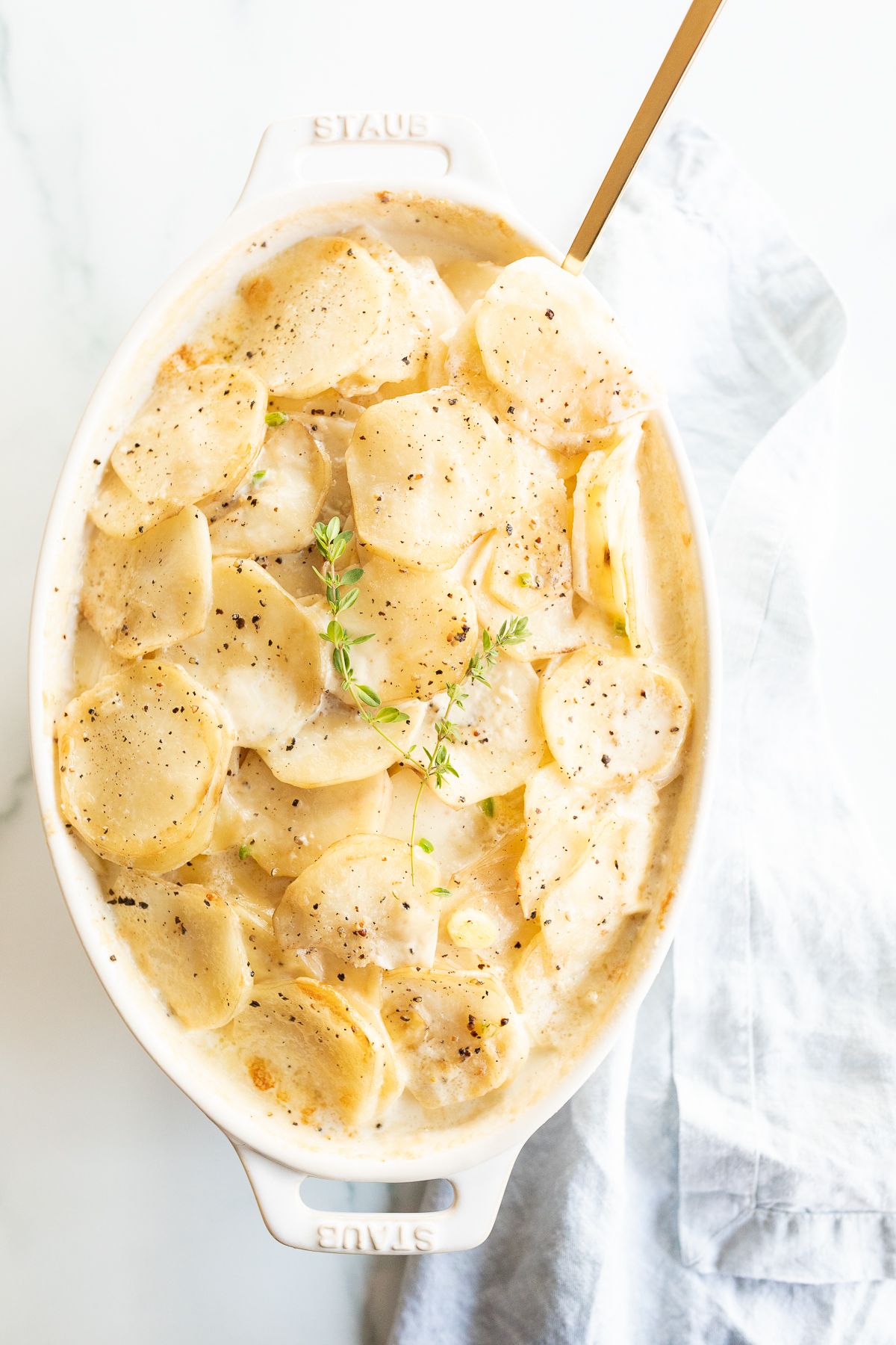 Gratin Dauphinoise potatoes in a white oval baking dish.