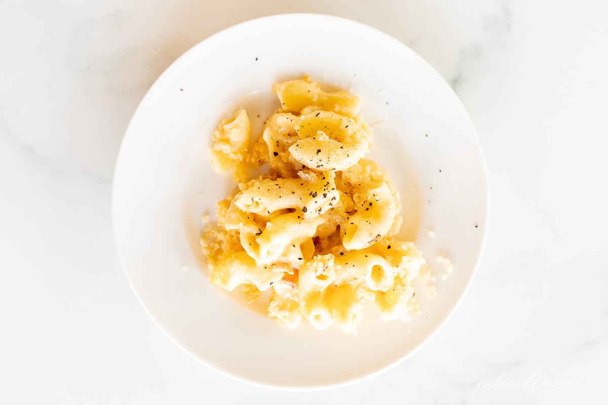 Bacon mac and cheese on a white plate.